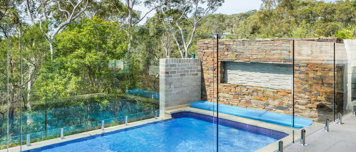 New pool and terrace at Balmoral, set against a sandstone wall with the treetops beyond
