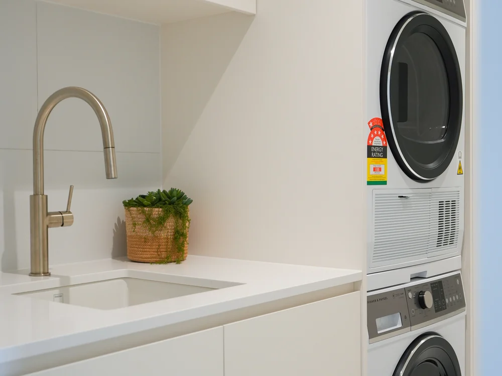 Laundry with a stacked washer and dryer behind cabinetry
