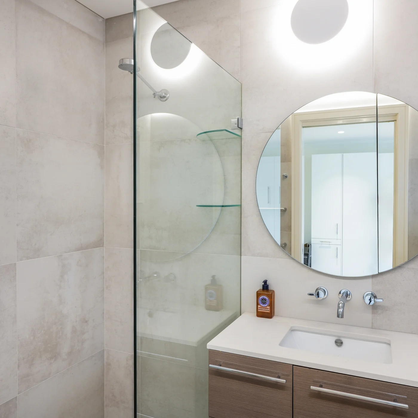 Bathroom at the Mosman studio, floating timber vanity and a round mirror under a skylight