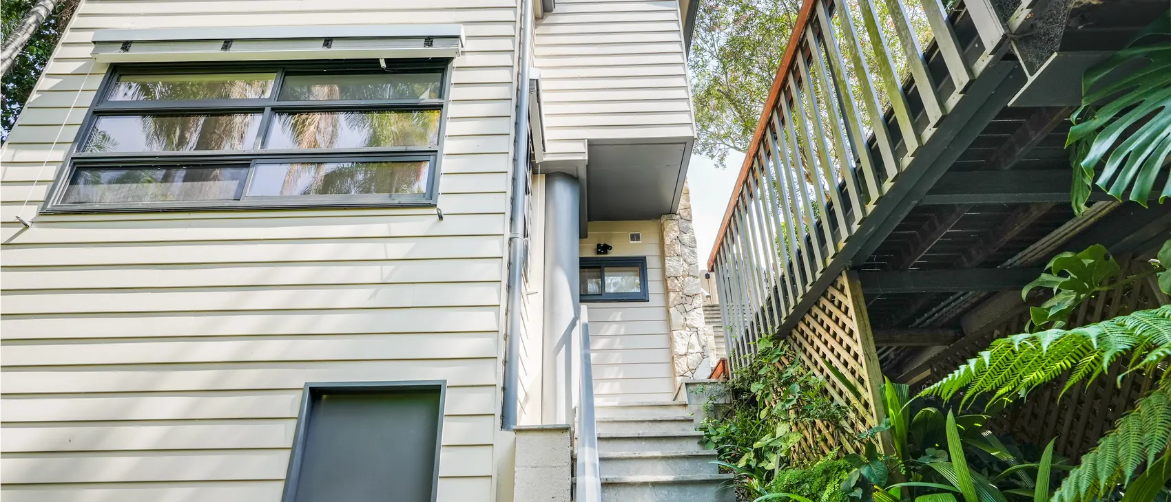The side of the Mosman studio among the palms, the external stair climbing the site