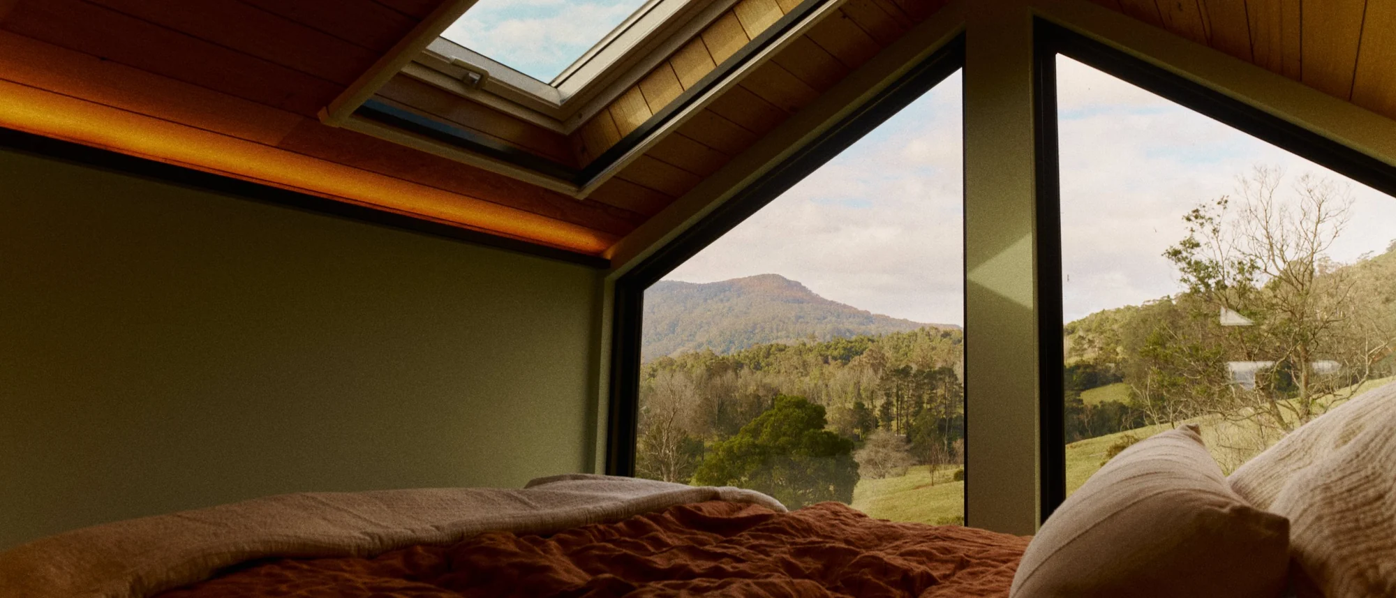 Loft bed under a skylight, the gable window framing the valley