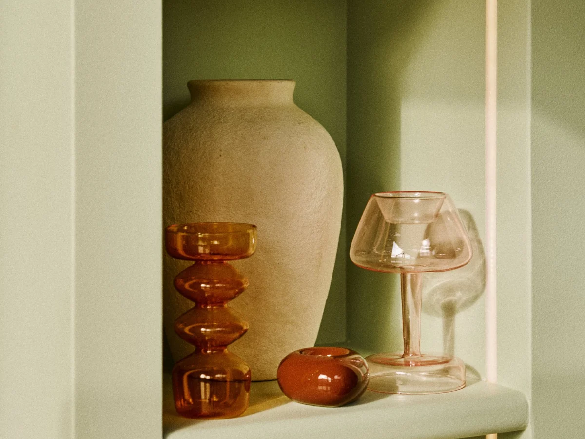 Built-in green shelving with terracotta and amber glass